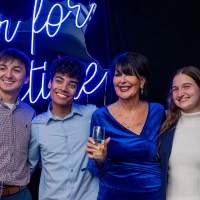 Group of friends and President Mantella standing in front of Laker for a Lifetime neon sign